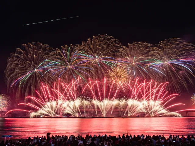 Fireworks bursting over Gwangan Bridge as crowds watch from the beach