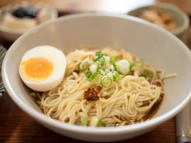A bowl of Busan-style milmyeon noodles topped with a soft-boiled egg and scallions