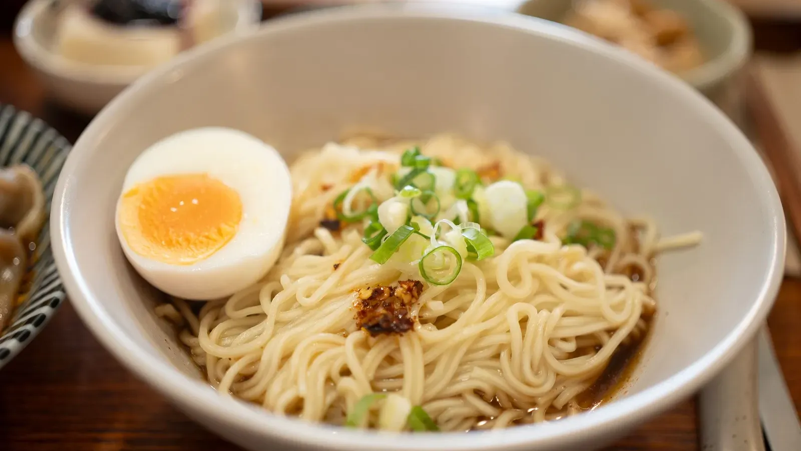 A bowl of Busan-style milmyeon noodles topped with a soft-boiled egg and scallions