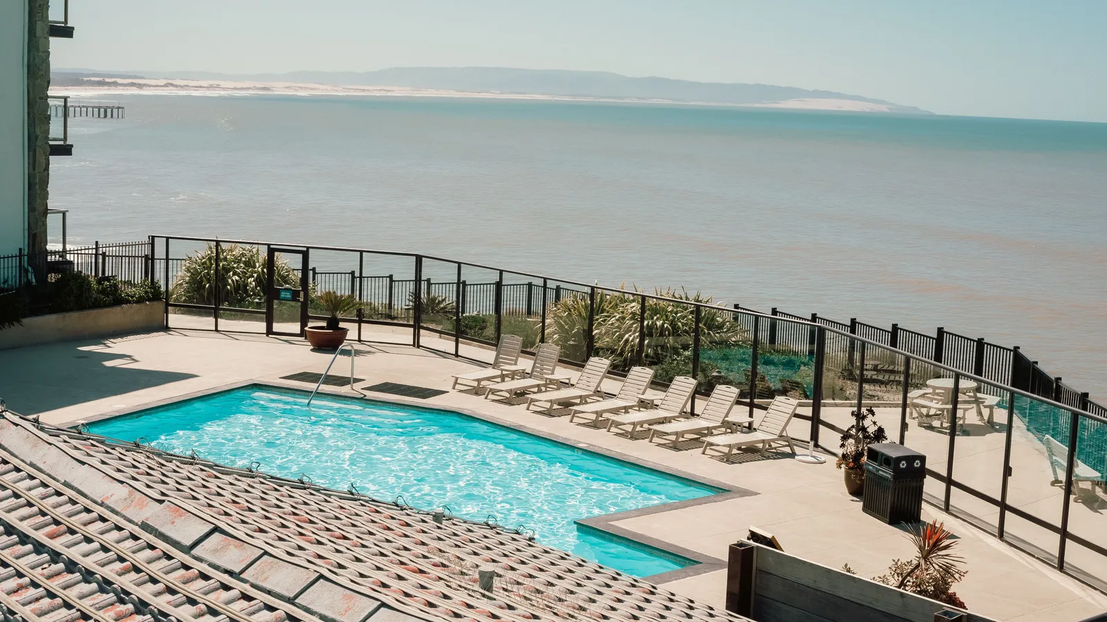 A hotel outdoor pool and loungers facing an open sea view