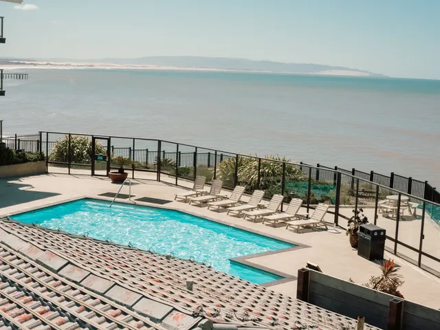A hotel outdoor pool and loungers facing an open sea view