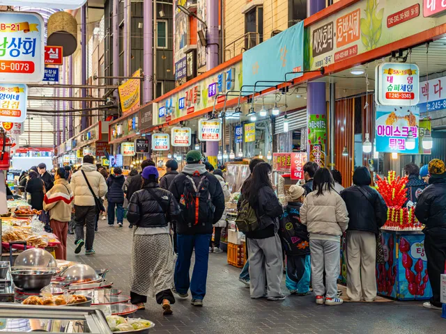 A crowded Nampo-dong market alley strung with flags and banners
