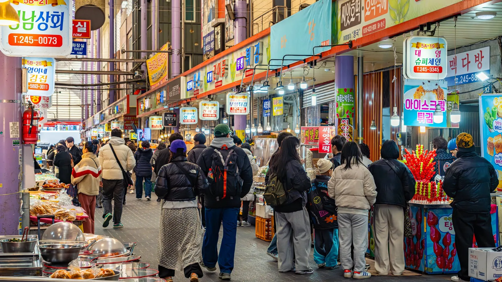 A crowded Nampo-dong market alley strung with flags and banners