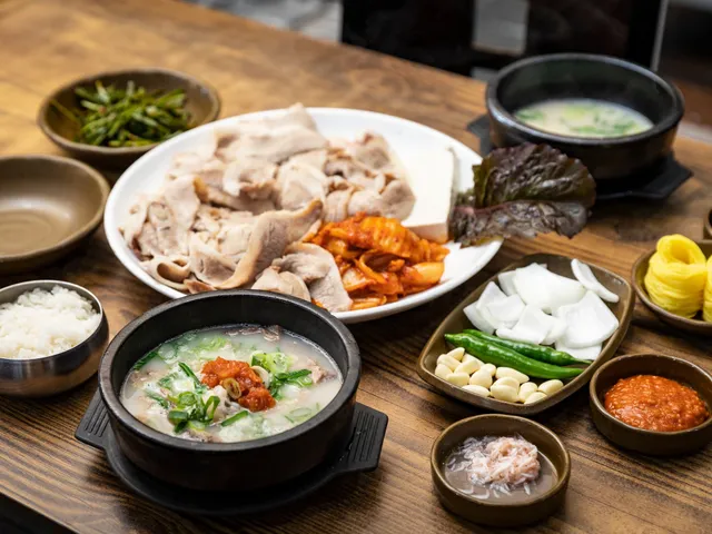 A dwaeji-gukbap set with a stone bowl of pork bone soup, sliced boiled pork, and kimchi
