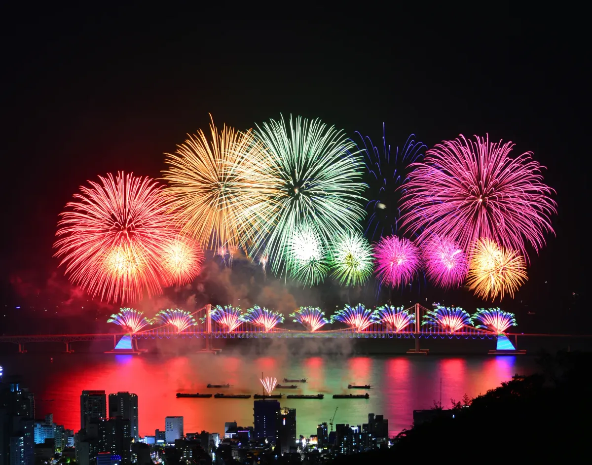 Elevated panoramic view of the fireworks over Gwangan Bridge from a hillside