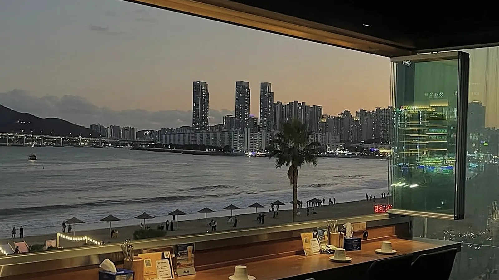 海辺のカフェの窓から望む広安里ビーチとマリンシティのスカイライン、高雄から直行便で約2.5時間