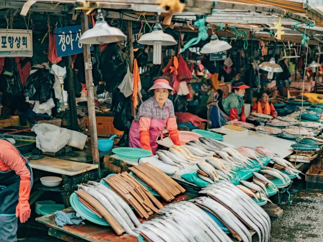 Fresh fish laid out at a Jagalchi Market stall with a vendor at work