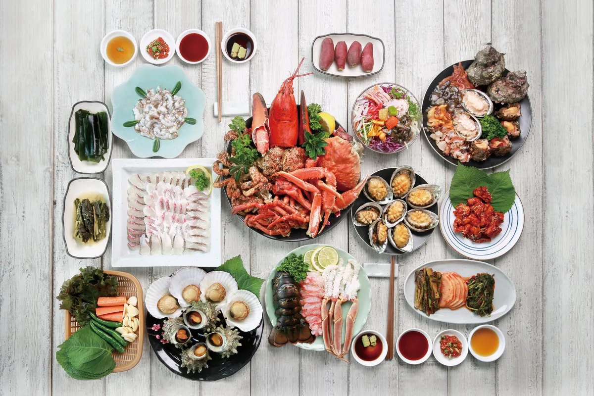 A spread of fresh Jagalchi seafood including king crab, lobster, sashimi, abalone, and scallops