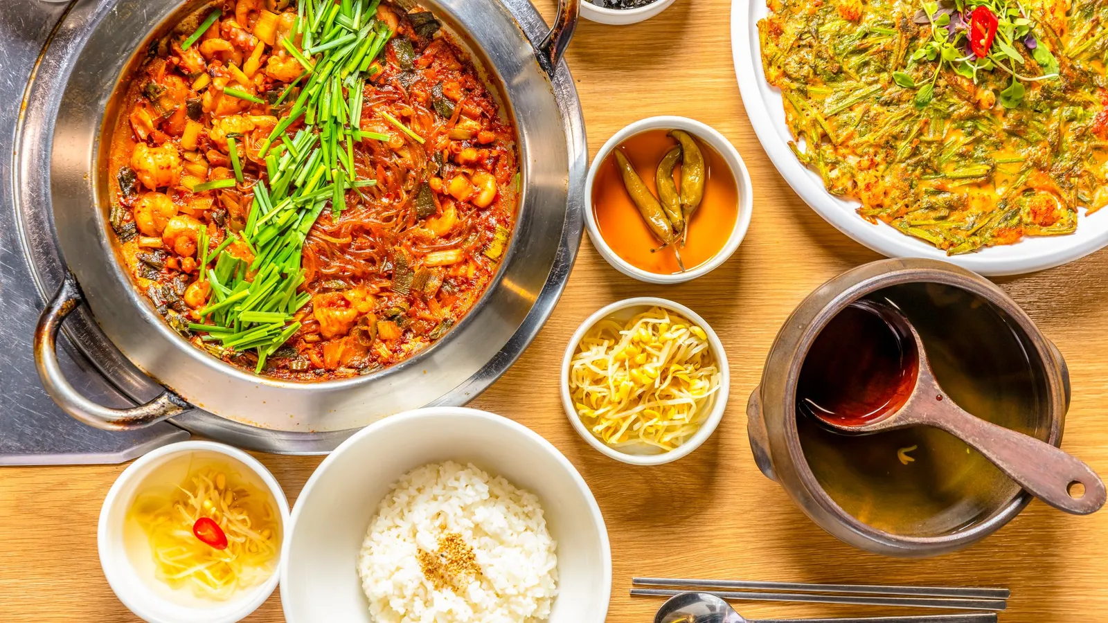 A pot of spicy octopus and rice cake stir-fry served with rice and side dishes