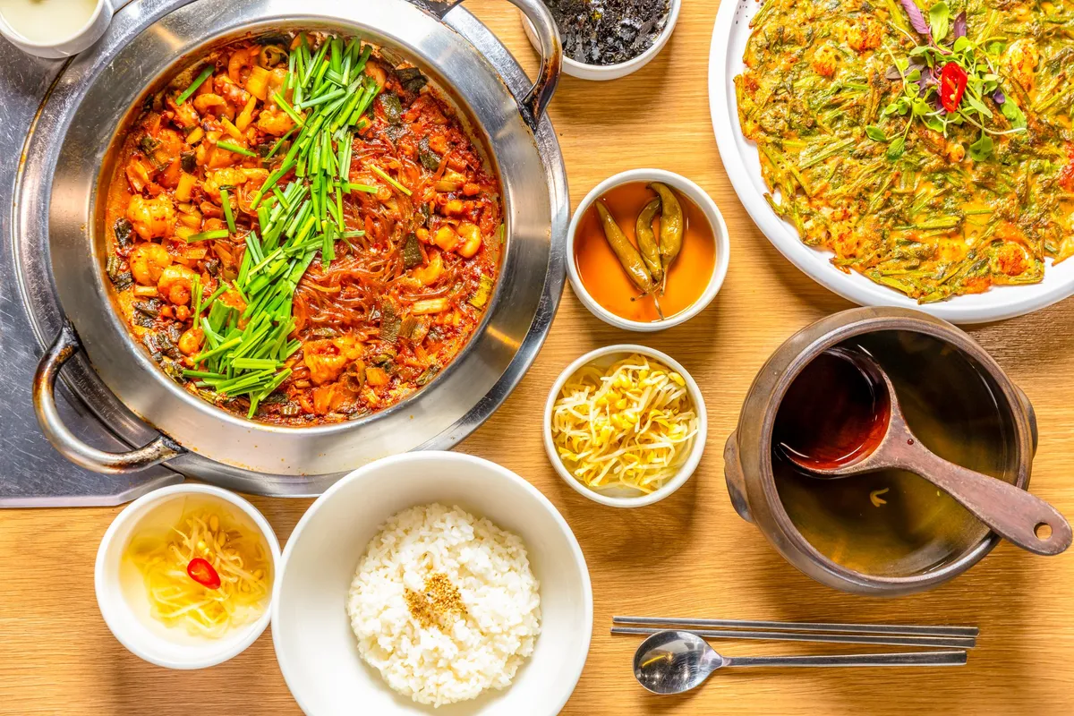 A pot of spicy octopus and rice cake stir-fry served with rice and side dishes