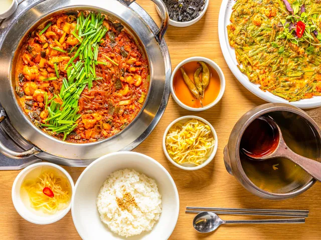 A pot of spicy octopus and rice cake stir-fry served with rice and side dishes