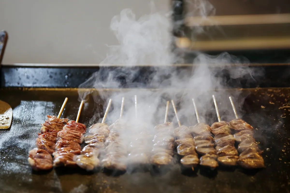Skewers of grilled street food smoking on a hotplate at a Busan market stall